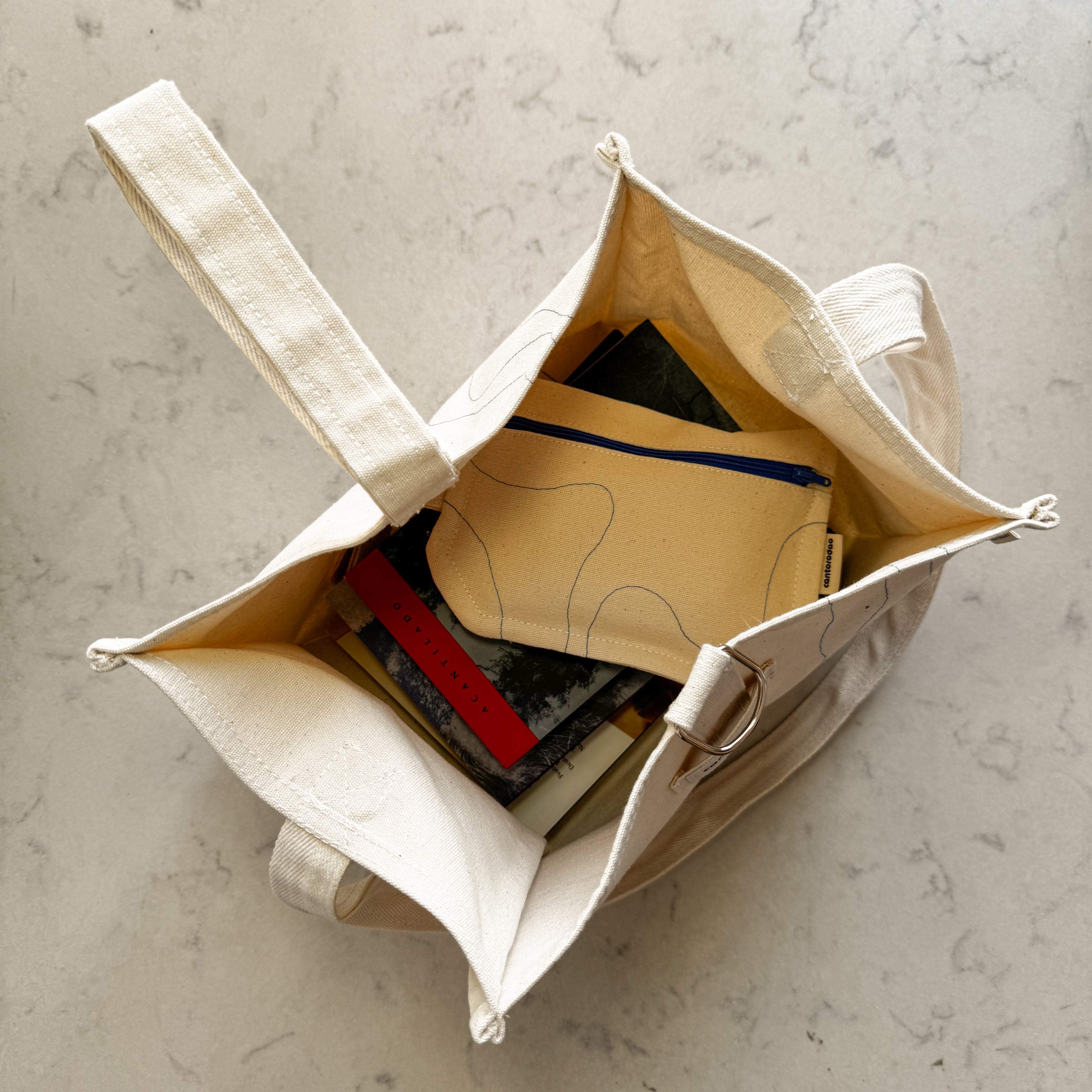 Porta libros artesanal lona cruda natural con asa bandolera y costura azul, Cantorodao